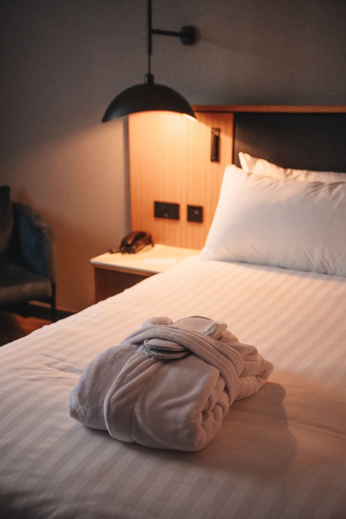 Crafting Captivating Headlines: Your awesome post title goes here A cozy hotel room featuring a plush robe on the bed under warm lighting, epitomizing comfort and relaxation.